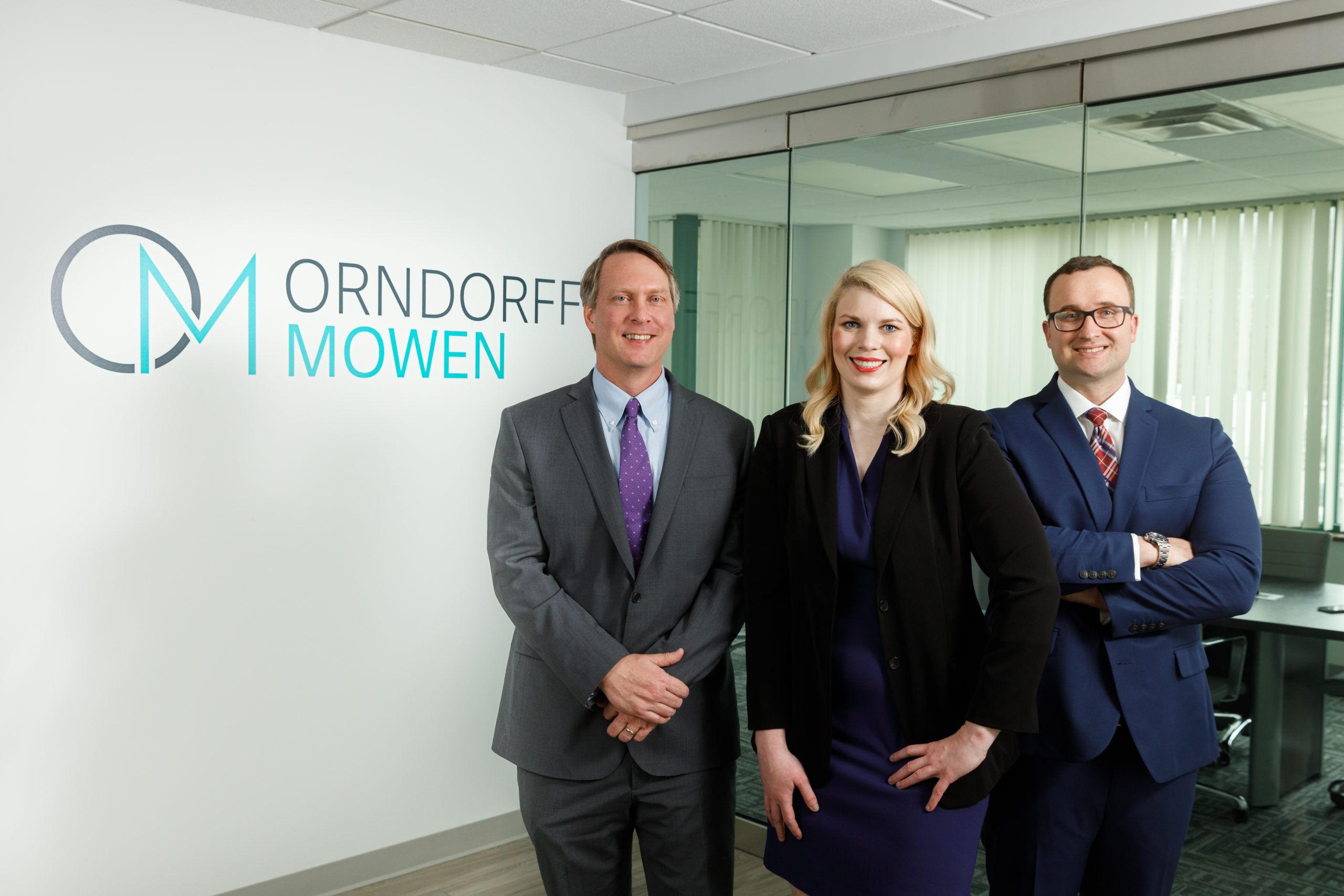 The managing partners of Orndorff Mowen in the office in front of their logo on the wall