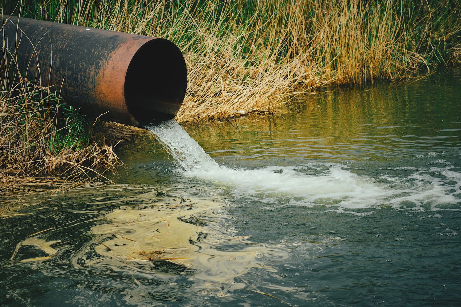 harmful waste water running into river from a pipe