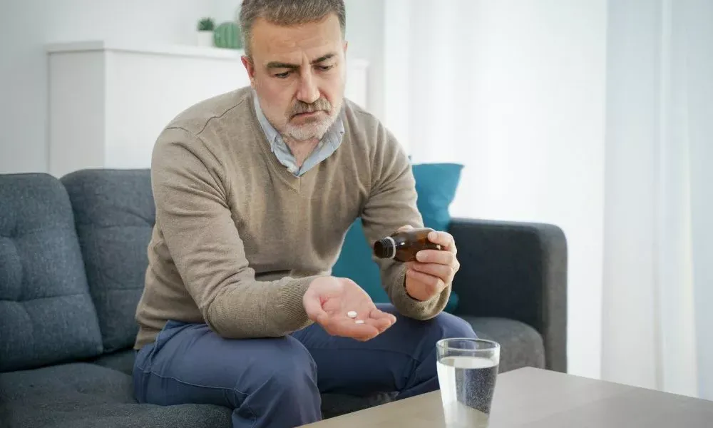 man holding prescription medication in one hand