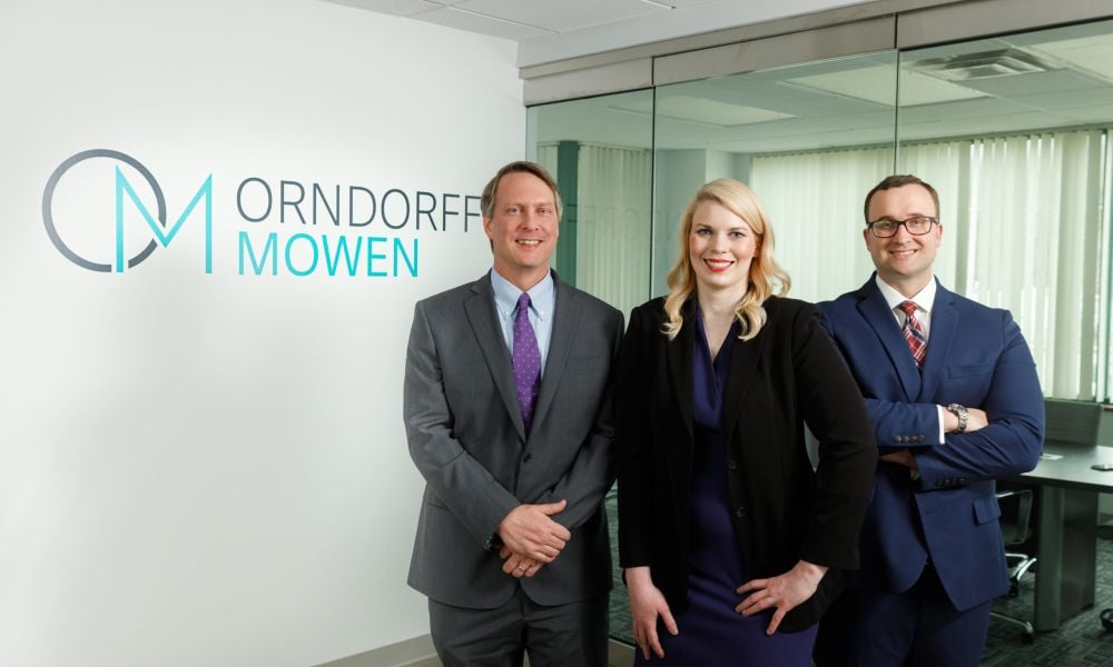 The managing partners of Orndorff Mowen in the office in front of their logo on the wall